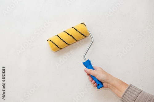 Painting roller in worker's hand. Repair in a room. Painting of walls