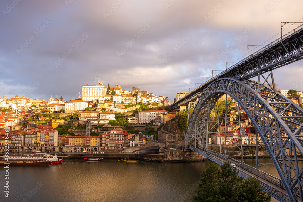 Morning in Porto Portugal: Douro river and Ribeira district featuring Ponte Luis I bridge and sunlit Episcopal palace on the top of the hill.