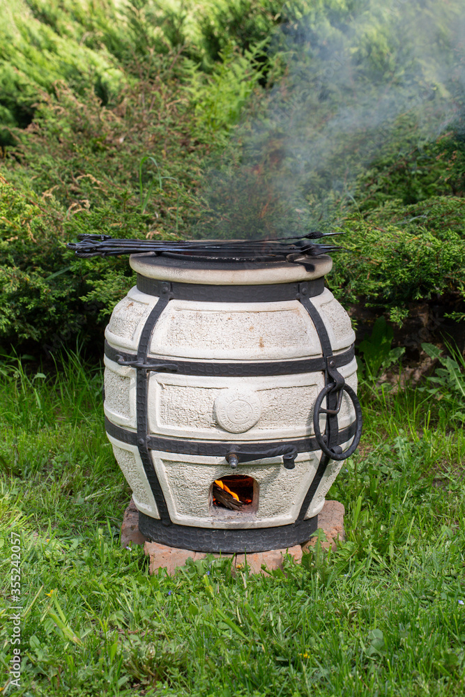 Burning smoking tandoor stands on the grass. Burning smoking tandoor stands on the grass.