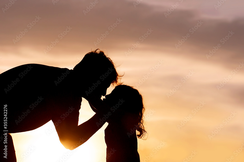 Silhouette of Loving Father Kissing his Young Child at Sunset
