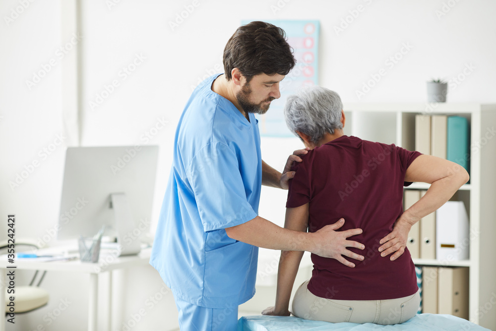 Obraz premium Male doctor examining the back of senior woman during her visit at hospital