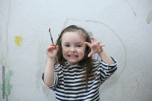 A child holds a brush in one hand, and scares with the other. The child thinks that She is a wolf. The child paints with watercolors on the wall, until his parents see. Unattended child.