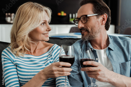 Beautiful woman smiling at husband while toasting with wine at home