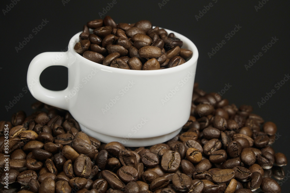 White mug with coffee grains sprinkled with coffee grains on a background White mug with coffee grains sprinkled with coffee grains on a background
