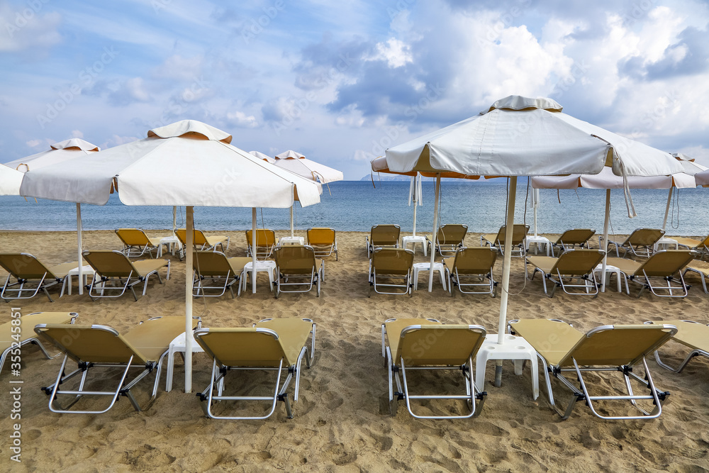 Desert beach with deck chairs and umbrellas waiting for tourists after quarantine. Fantastic white sand, sea and mountain. 2020 summer travel. Relax places island Crete, Greece.