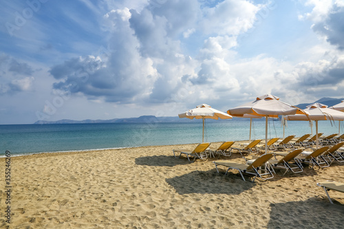 Desert beach with deck chairs and umbrellas waiting for tourists after quarantine. Fantastic white sand  sea and mountain. 2020 summer travel. Relax places island Crete  Greece. Free space for text.