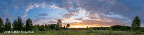 Sunset landscape panorama of summer meadow under blue sky with clouds