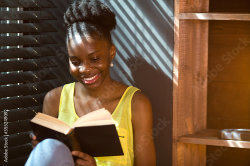  beautiful young african woman reading a book indoors 