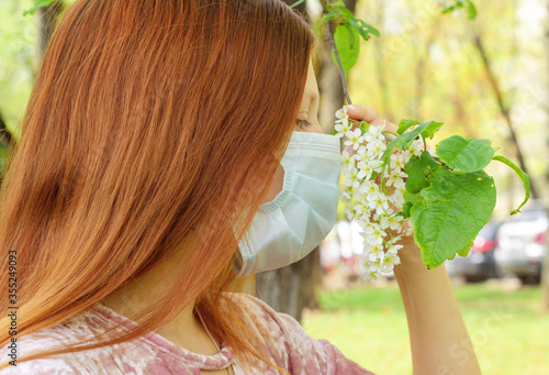 a girl smell a flowering cherry tree during quarantine due to the coronavirus pandemic outdoor