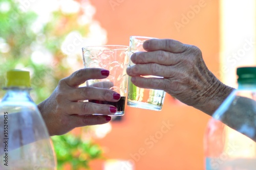 two hands holding glass of water, cheering