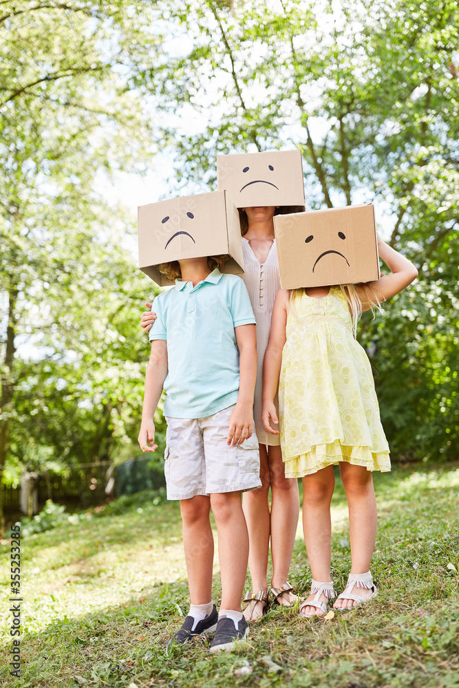 Familie mit Kindern im Garten unter Pappkartons Familie mit Kindern im Garten unter Pappkartons