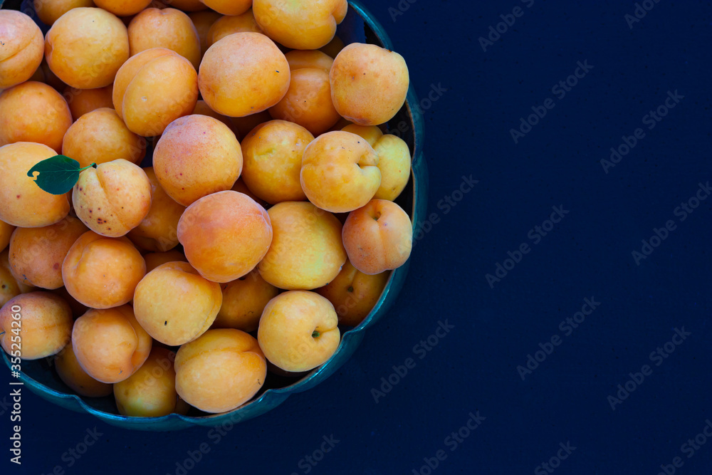 Fresh, organic apricot fruit spilling out of a on dark blue background. Imperfect, orange, seasonal fruits for healthy eating and lifestyle. Space for text Fresh, organic apricot fruit spilling out of a on dark blue background. Imperfect, orange, seasonal fruits for healthy eating and lifestyle. Space for text