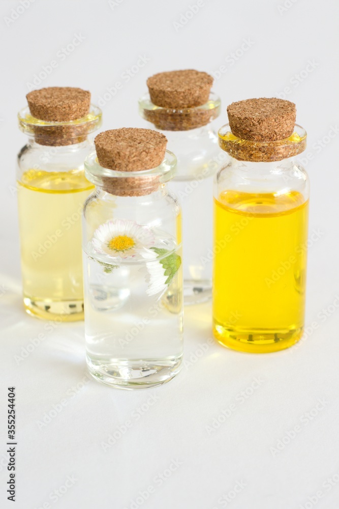 Beautiful photo of small bottles with cork stoppers filled with fantastic fragrant oils, essential oils, rose water and daisies Beautiful photo of small bottles with cork stoppers filled with fantastic fragrant oils, essential oils, rose water and daisies
