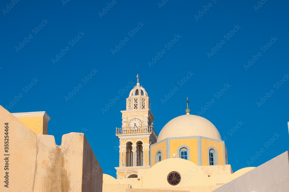 Church dome and clock tower in a Mediterranean style against a bright blue sky