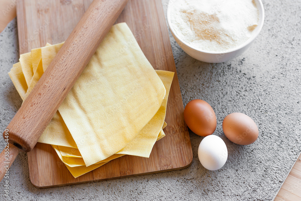 Ingredients for homemade lasagna. Rolling pin, flour, eggs and fresh lasagna sheets. Selective focus. Top view Ingredients for homemade lasagna. Rolling pin, flour, eggs and fresh lasagna sheets. Selective focus. Top view