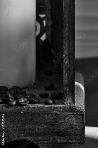 coffee beans trickling out of a wooden lantern, black and white