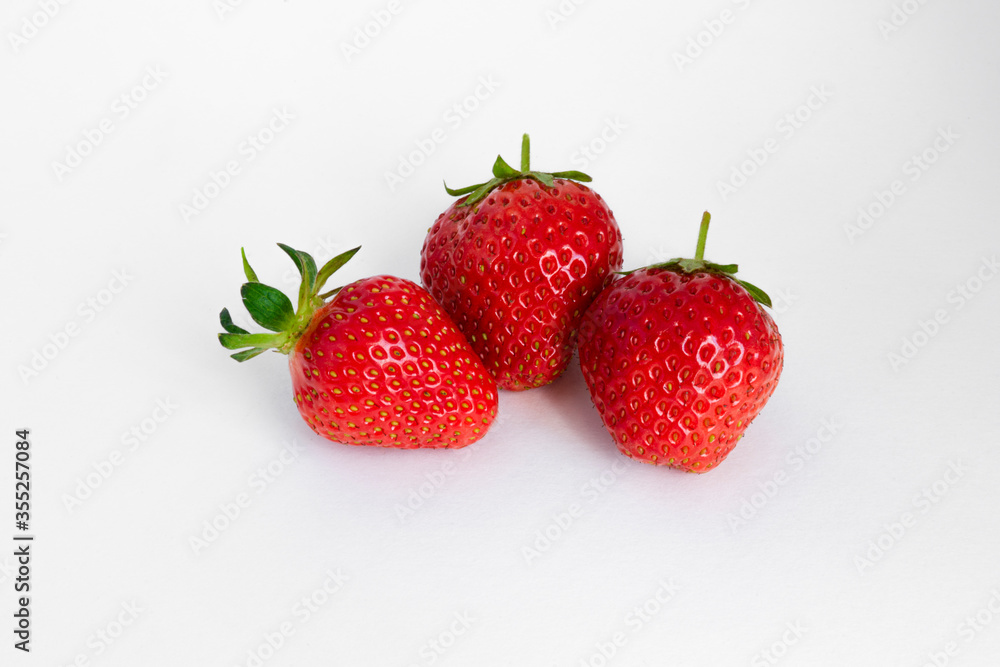 three red strawberries on a white background three red strawberries on a white background