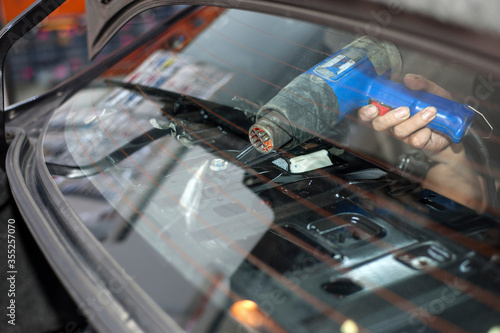 Penang, Malaysia - January 21, 2020 : Car window tinting specialist attaching vinyl tinting film to car window using heat gun.