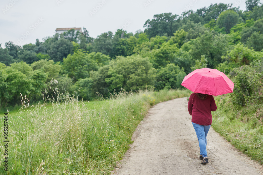 woman walking on a green path with a red umbrella