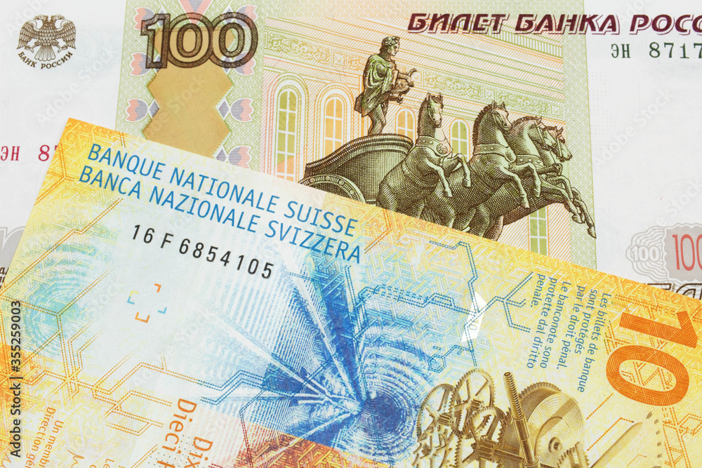 A macro image of a Russian one hundred ruble note paired up with a yellow Swiss ten franc bill.  Shot close up in macro.