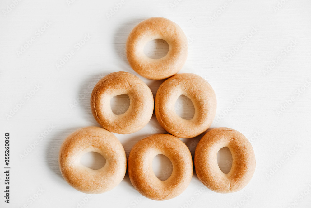 Drying or mini round bagels in the shape of a pyramid on a white wooden background. Top view. Copy, empty space for text