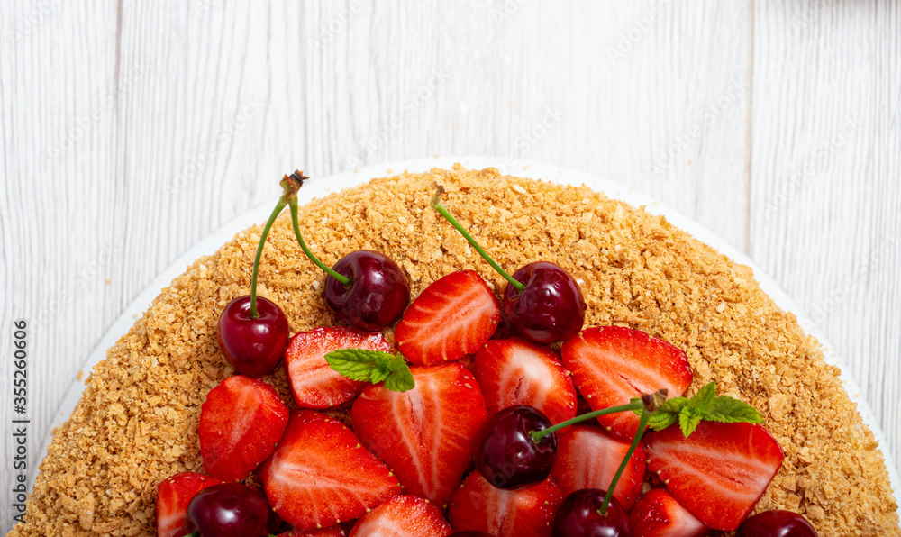 Beautiful napoleon cake with strawberries and cherries mixed with i mint on a light background Beautiful napoleon cake with strawberries and cherries mixed with i mint on a light background