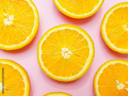 Slices of juicy orange oranges on a bright pink background.