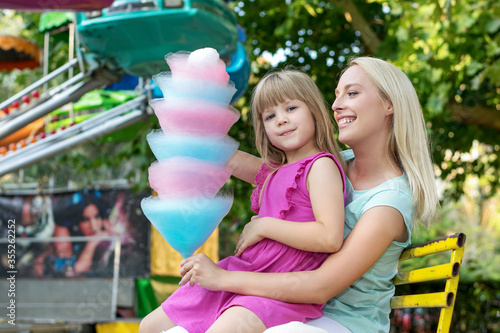 Happy mother and daughter have fun in amusement carnival park