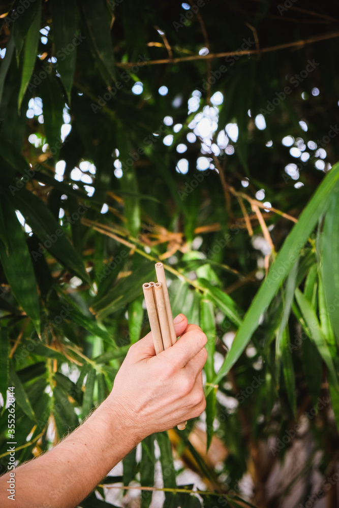 Reusable Bamboo drinking straw in man hands on bamboo background. Zero waste concept Reusable Bamboo drinking straw in man hands on bamboo background. Zero waste concept