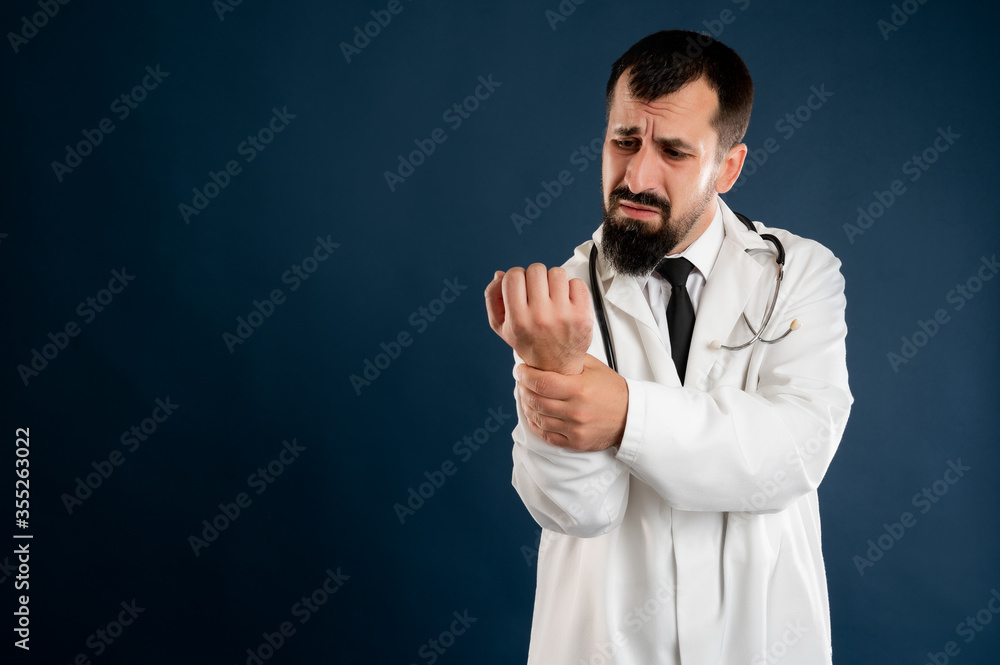 Fototapeta premium Male doctor with stethoscope in medical uniform has wrist pain