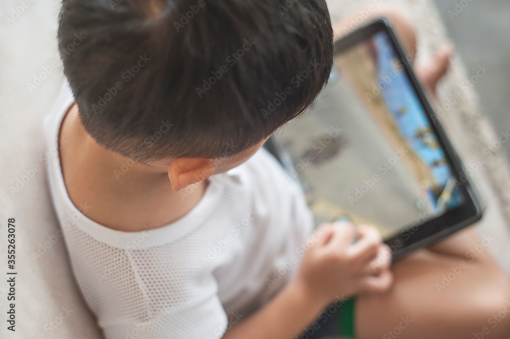 Penang, Malaysia - January 14, 2020 : Little kid's using digital touchscreen phone tablet computer playing games. Penang, Malaysia - January 14, 2020 : Little kid's using digital touchscreen phone tablet computer playing games.
