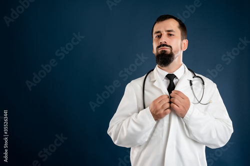 Male doctor with stethoscope in medical uniform arranges his collar