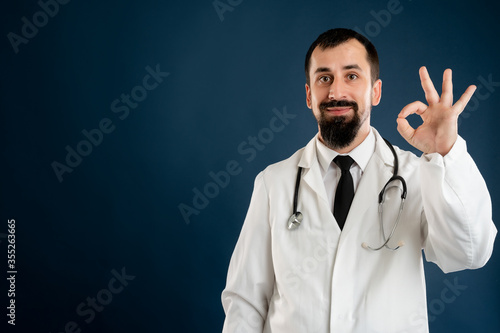 Male doctor with stethoscope in medical uniform showing OK sign