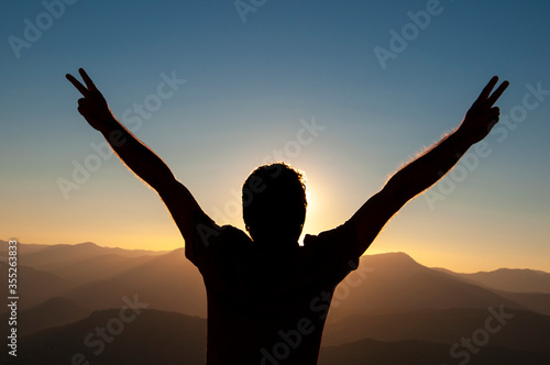 Silhouette young man celebrating success on top of a mountain at sunrise. Business, leadership, achievement and people concept. Business success concept. power, travel, peace