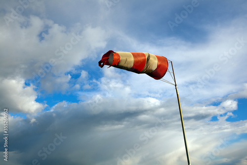 Meteorology wind bag for marine navigation. Red and white windsock blows against a blue sky