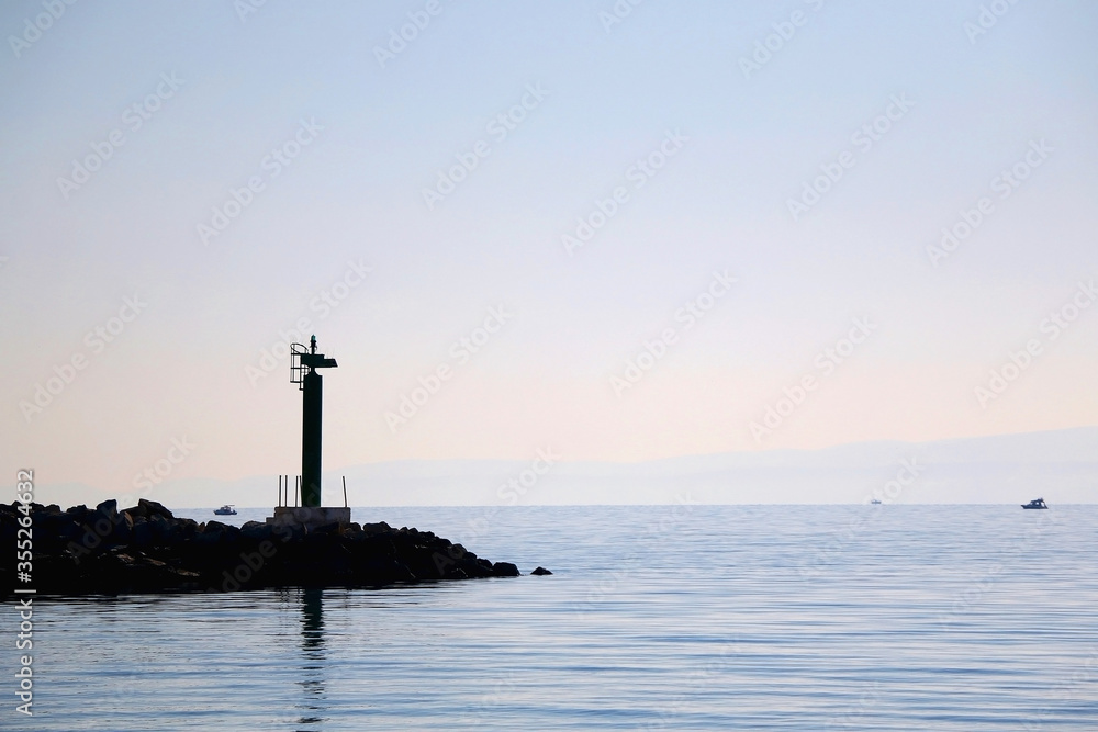 Silhouette of a small lighthouse on a pier in Split, Croatia.