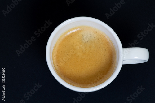 White cup of coffee from the zenith on black background