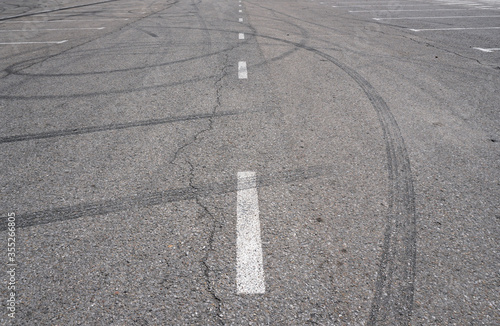 Asphalt texture with white line and tire marks.  Smooth asphalt road. Tarmac dark grey grainy road background.Top view