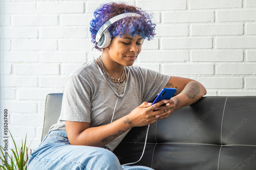 © carballo - young afro american girl listening to music on the phone on the sofa
