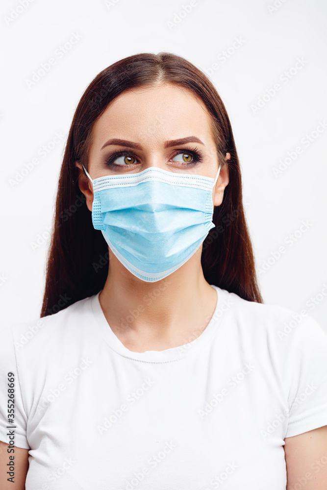 Brunette woman wearing disposable mask shows emotions with her eyes Brunette woman wearing disposable mask shows emotions with her eyes