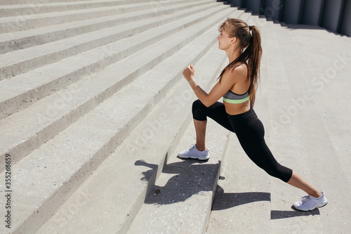 Pilates trainer doing stretching exercise and developing inner thigh muscles on stairs in the park