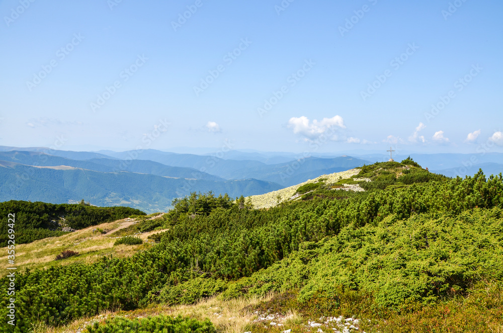 Wooden Cross on top of Mount Strymba on a background of mountains alpine vegetation stones on a sunny day near the village of Kolochava, Carpathians Ukraine. Wooden Cross on top of Mount Strymba on a background of mountains alpine vegetation stones on a sunny day near the village of Kolochava, Carpathians Ukraine.