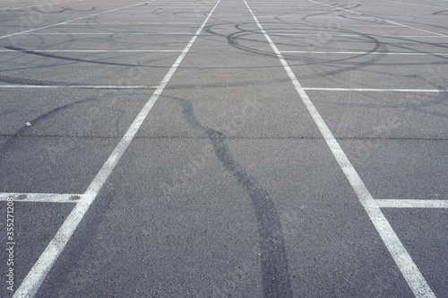 Fototapeta Naklejka Na Ścianę i Meble -  Asphalt texture with white line and tire marks.  Smooth asphalt road. Tarmac dark grey grainy road background.Top view