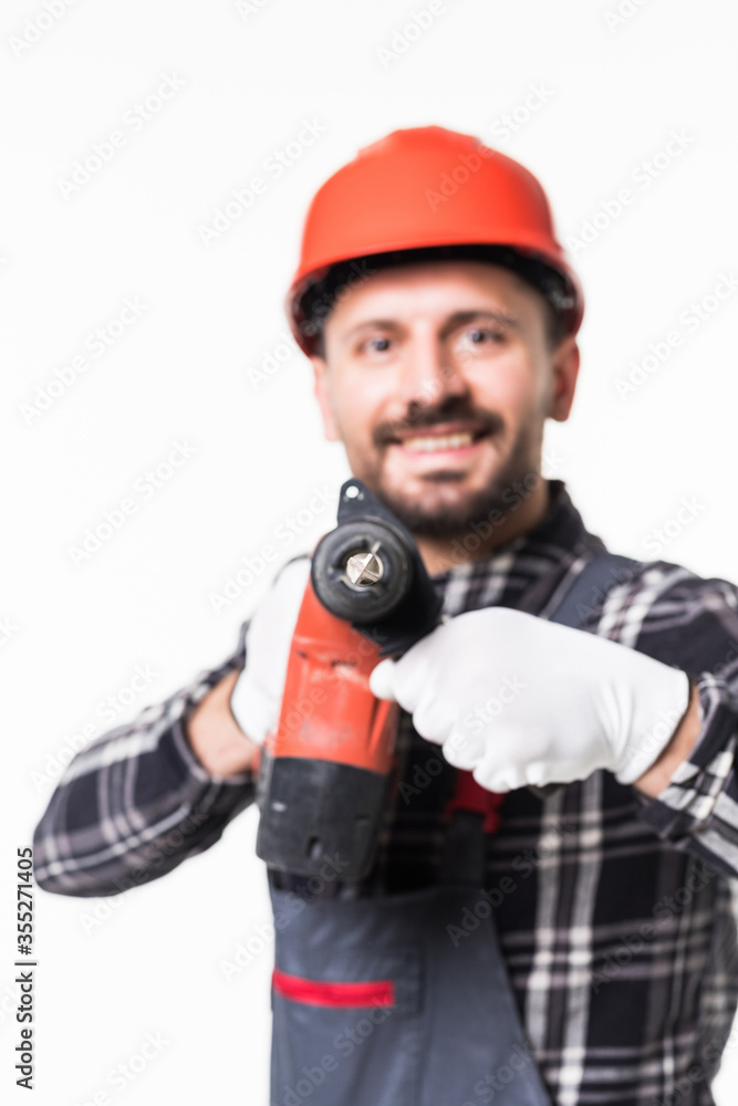 Handsome handyman in uniform with tool belt holding drill isolated on white