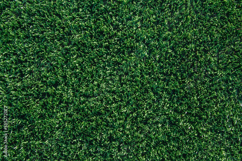 Green grass and white border lines on football ground. Soccer field on artificial turf. Artificial green grass texture. Artificial football field in an open stadium