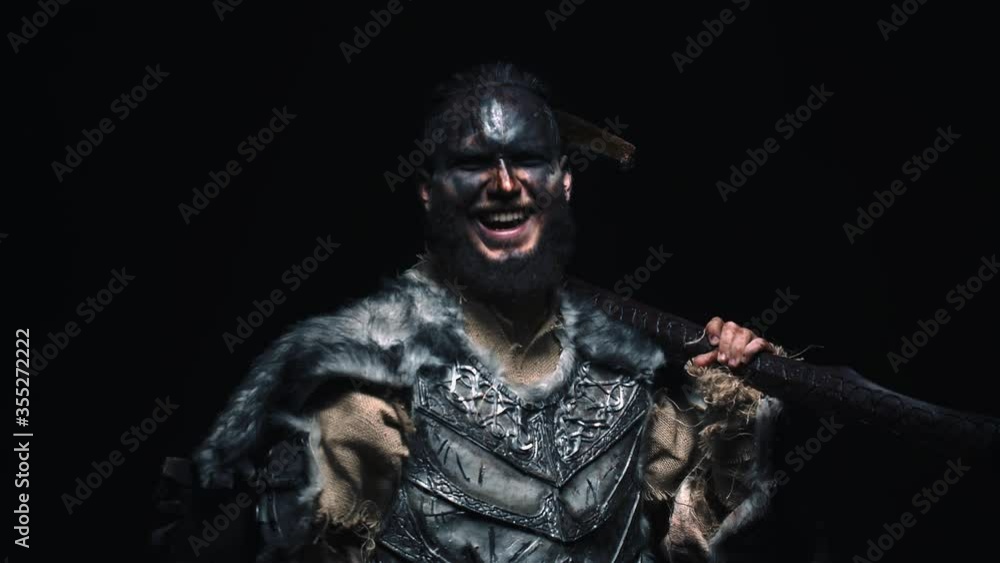 The Viking puts the axe on his shoulder, says a battle speech and laughs madly. The possessed Viking in armor with an axe laughs madly looking at the camera The Viking puts the axe on his shoulder, says a battle speech and laughs madly. The possessed Viking in armor with an axe laughs madly looking at the camera