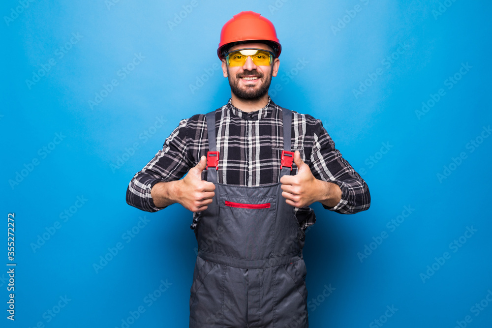 Portrait of happy handyman with tools showing thumbs up sign isolated on blue background Portrait of happy handyman with tools showing thumbs up sign isolated on blue background