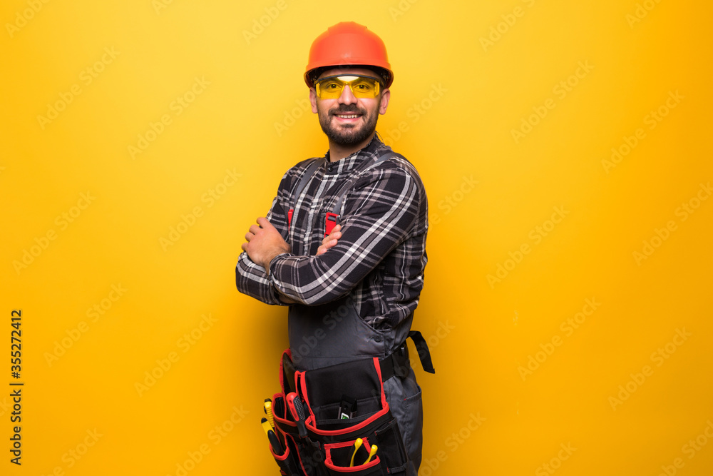 Portrait of happy handyman with tool belt isolated on yellow background Portrait of happy handyman with tool belt isolated on yellow background