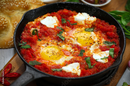 Shakshuka. Fried eggs in tomato sauce, with tomatoes and hot peppers, in a cast-iron frying pan.
