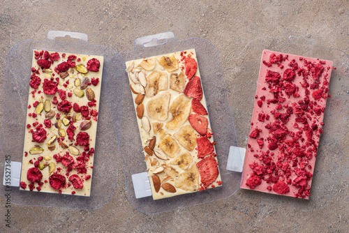 Handmade chocolate bars with freeze dried berries and walnut in molds.